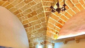 A dining area with a high, textured ceiling, a table with four chairs, and a bottle of wine. - TS Residence (Sannicola)