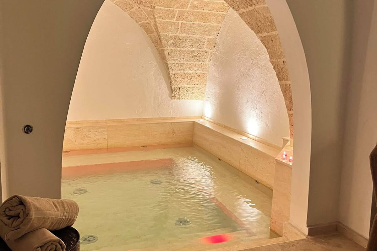A spa room with a stone archway leading to a small pool.