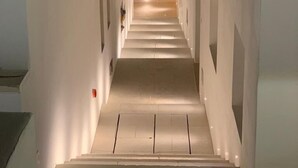 A narrow, well-lit staircase with white walls and a wooden ceiling. - TS Residence (Sannicola)