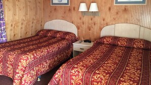Ein Hotelzimmer mit zwei Betten, Holzvertäfelung und zwei gerahmten Blumenbildern.
