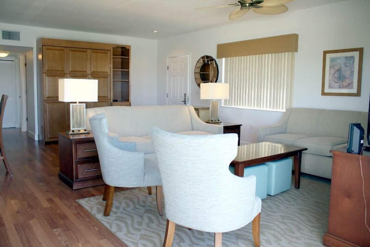 A modern living room with a sofa, two armchairs, a coffee table, and a wooden cabinet.