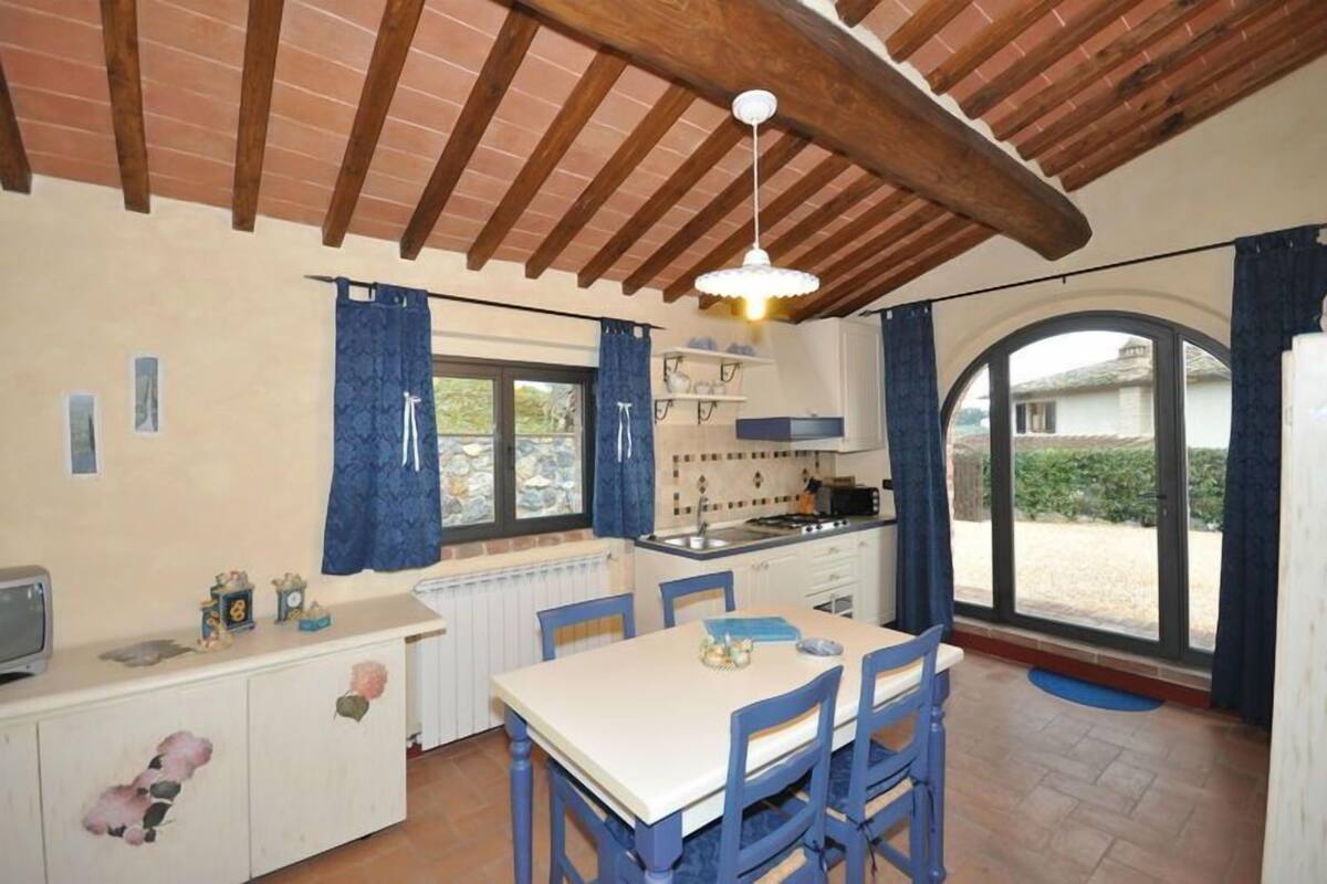 A kitchen with a dining area, wooden beams, a window, and a view of the outside.
