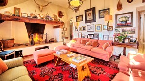 A cozy living room with a fireplace, a pink sofa, and a coffee table. - Il Principe (Manciano)