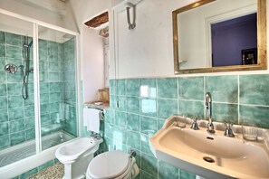 A bathroom with a shower, toilet, sink, and a mirror. - Marsilia (Manciano)