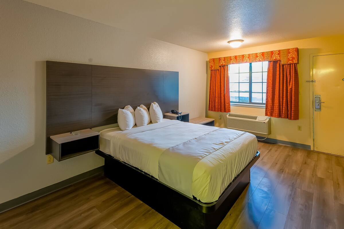 Une chambre d’hôtel avec un lit, une table de chevet et une fenêtre avec des rideaux.