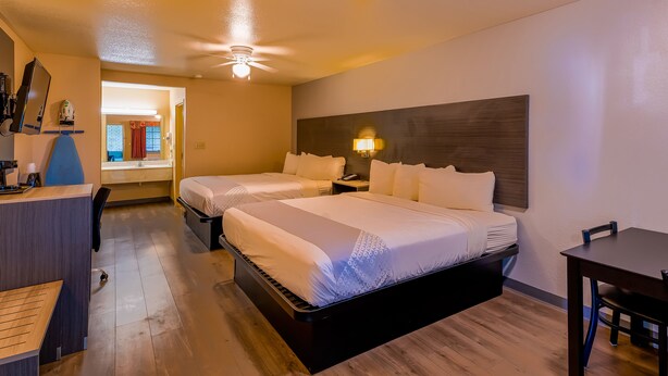 A hotel room with two beds, a desk, a chair, a nightstand, and a ceiling fan. - OYO Hotel Yoakum West (Yoakum)