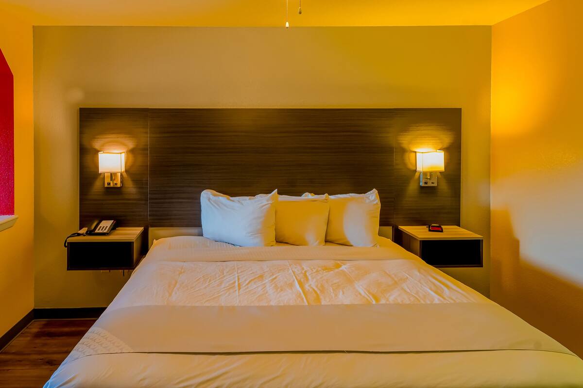 Une chambre d’hôtel avec un grand lit, deux tables de chevet avec des lampes et une tête de lit en bois.