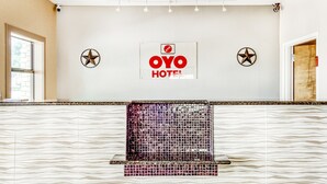 A reception area with a 'OYO HOTEL' sign, two star decorations, and a patterned wall. - OYO Hotel Yoakum West (Yoakum)