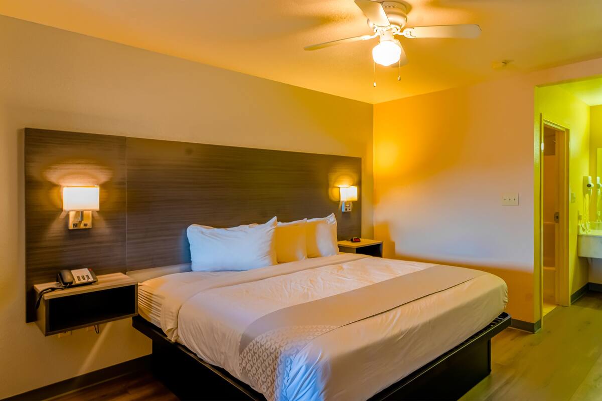 Une chambre d’hôtel avec un grand lit, des lampes de chevet, un ventilateur de plafond et un téléphone sur la table de chevet.