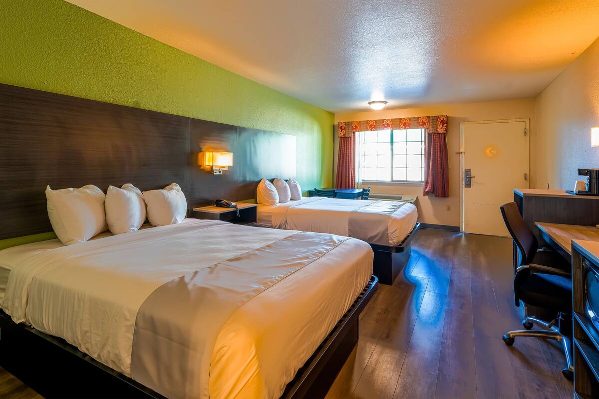 Une chambre d’hôtel avec deux lits, un bureau et une chaise.