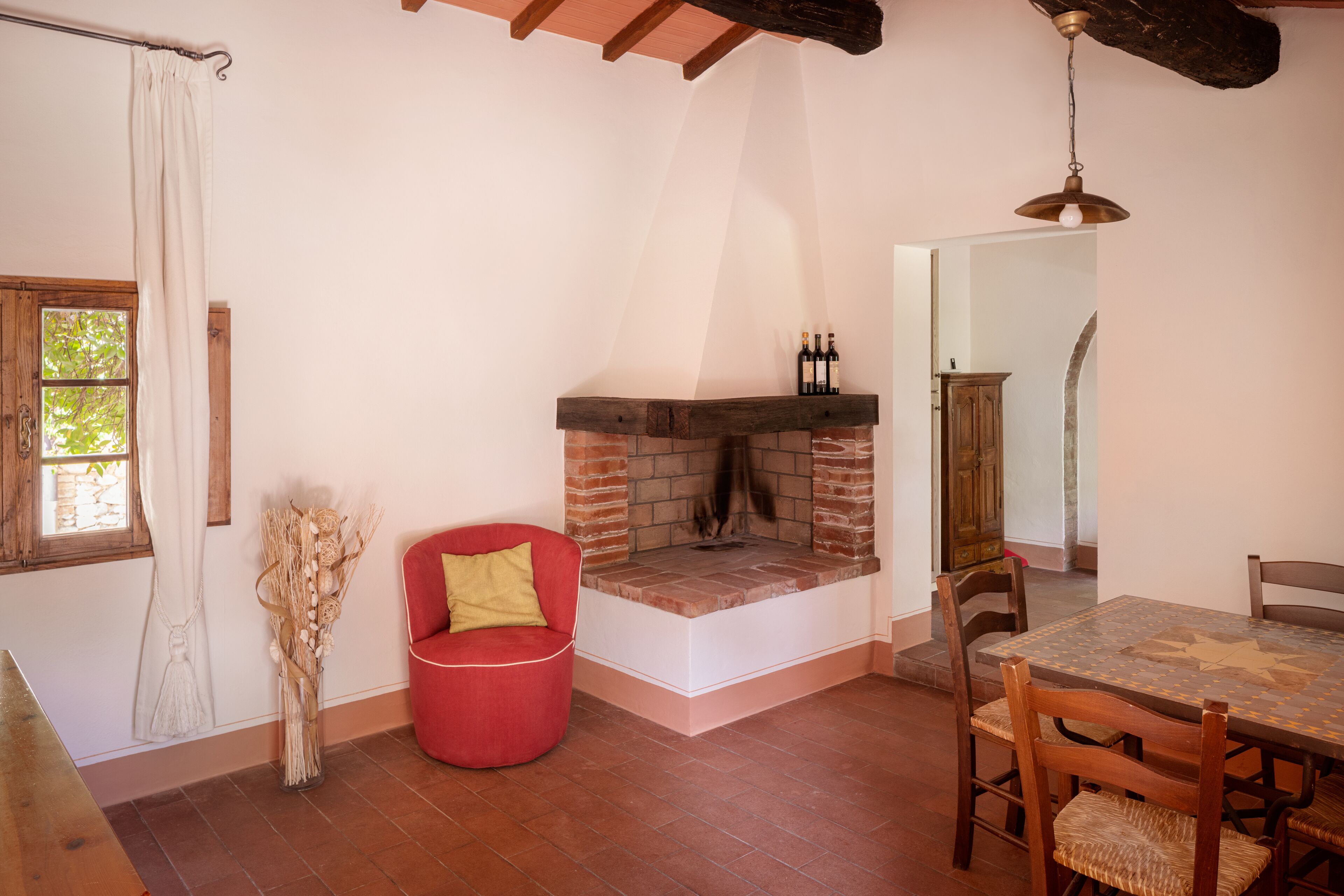 A cozy room with a fireplace, a dining table, and a red chair.