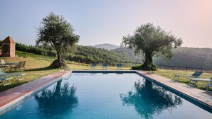 A swimming pool with a clear view of the surrounding landscape, including trees and distant hills. - Castello di Bossi (Castelnuovo Berardenga)