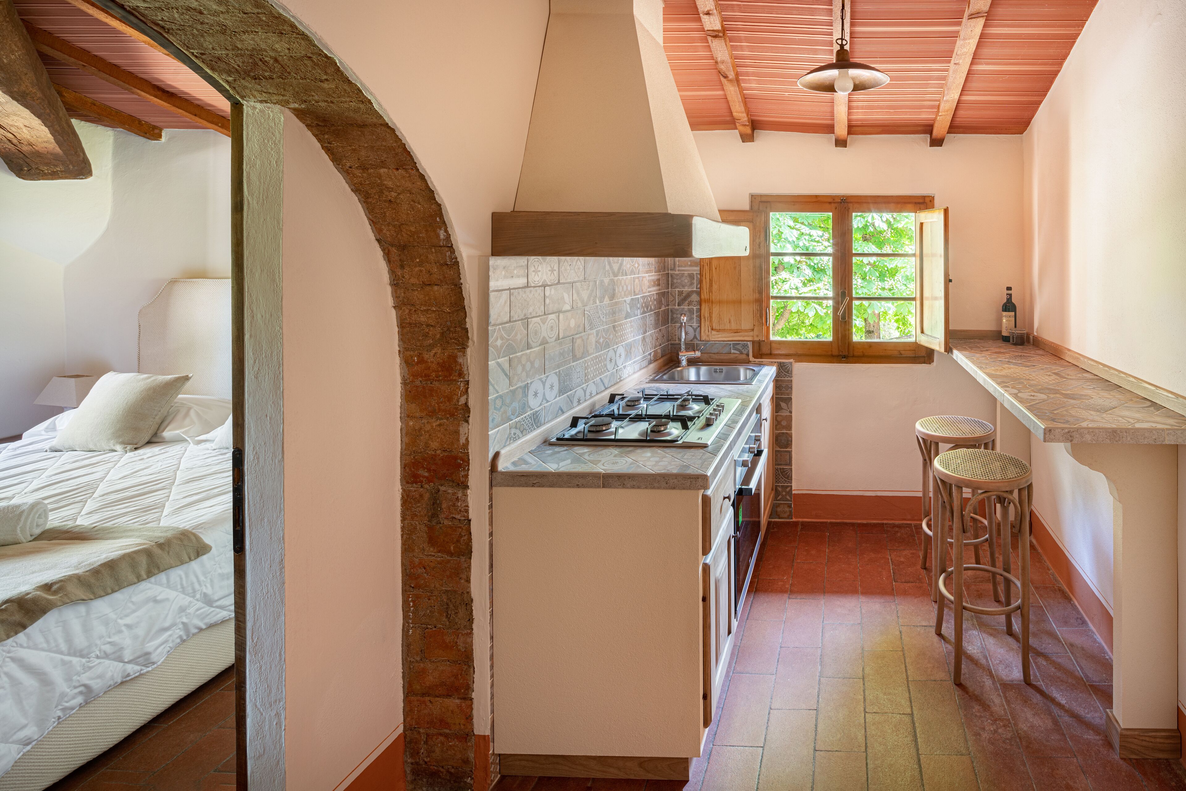 A compact kitchen with a gas stove, a sink, and a window with a view of greenery.