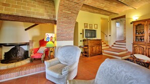 Uma sala de estar com lareira, televisão e escada que leva a outro andar.