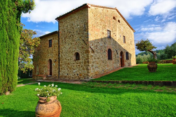 A stone building with a sloped roof, a central entrance, and a small porch. - Villa Rachele (Casole d'Elsa)