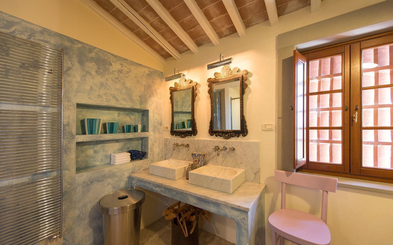 A bathroom with two sinks, a mirror, a window, and a towel rack.