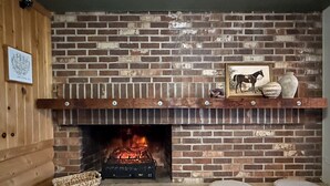 A brick fireplace with a mantel shelf displaying decorative items. - The Trail Inn - Grantsburg (Grantsburg)