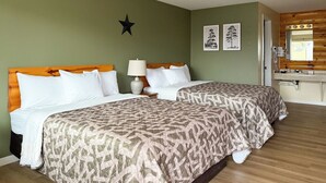 A double room with two beds, a wooden headboard, a bedside lamp, and a small mirror above the sink. - The Trail Inn - Grantsburg (Grantsburg)