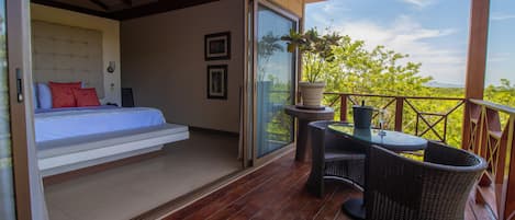 A bedroom with a bed, a small table, and a potted plant.