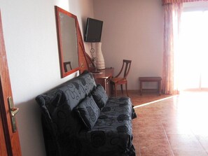 Un salon avec un canapé, un téléviseur, un fauteuil et une table.