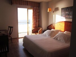 Una habitación de hotel con una cama, una silla, un escritorio y un cuadro en la pared.