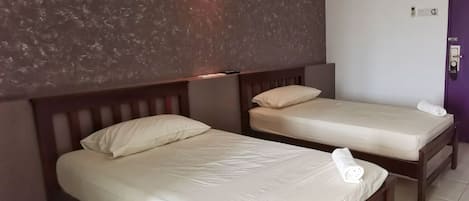 A hotel room with two single beds, a wooden headboard, a textured wall, and a purple door.