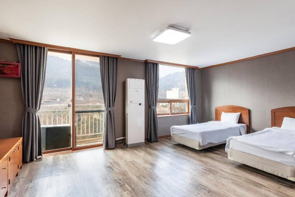 A hotel room with two beds, a wardrobe, a desk, and a balcony with a view.