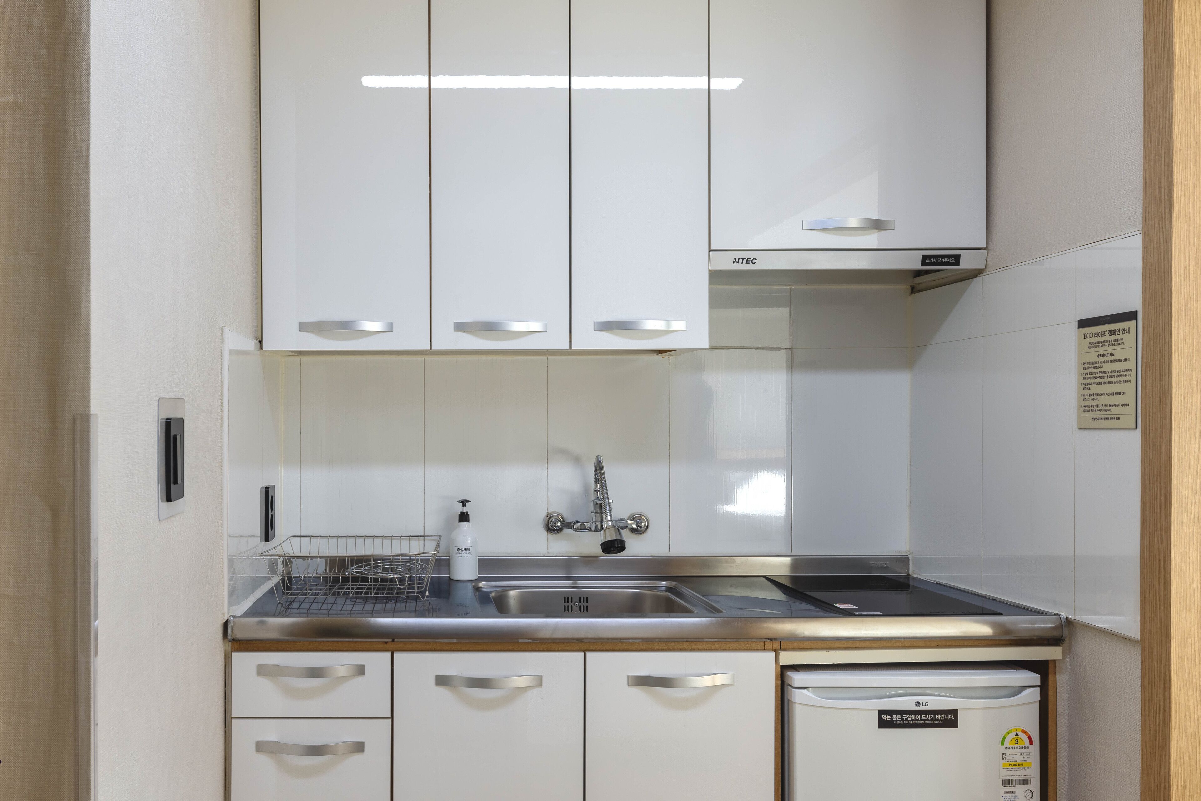 Uma cozinha compacta com armários brancos, eletrodomésticos de aço inoxidável e máquina de lavar louça embutida.