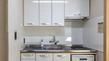A compact kitchen with white cabinets, stainless steel appliances, and a built-in dishwasher.