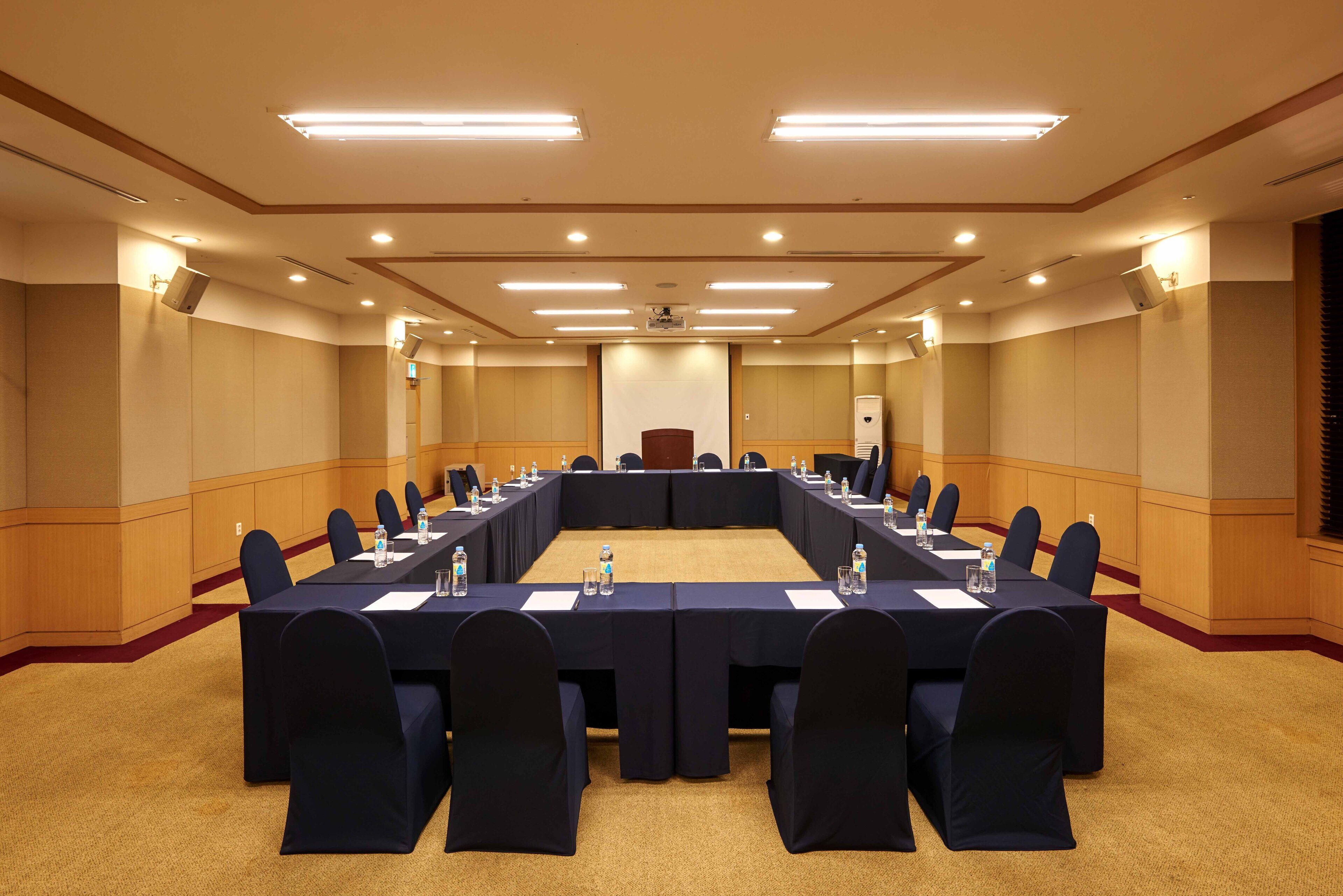 A conference room with a long table, chairs, and a podium.
