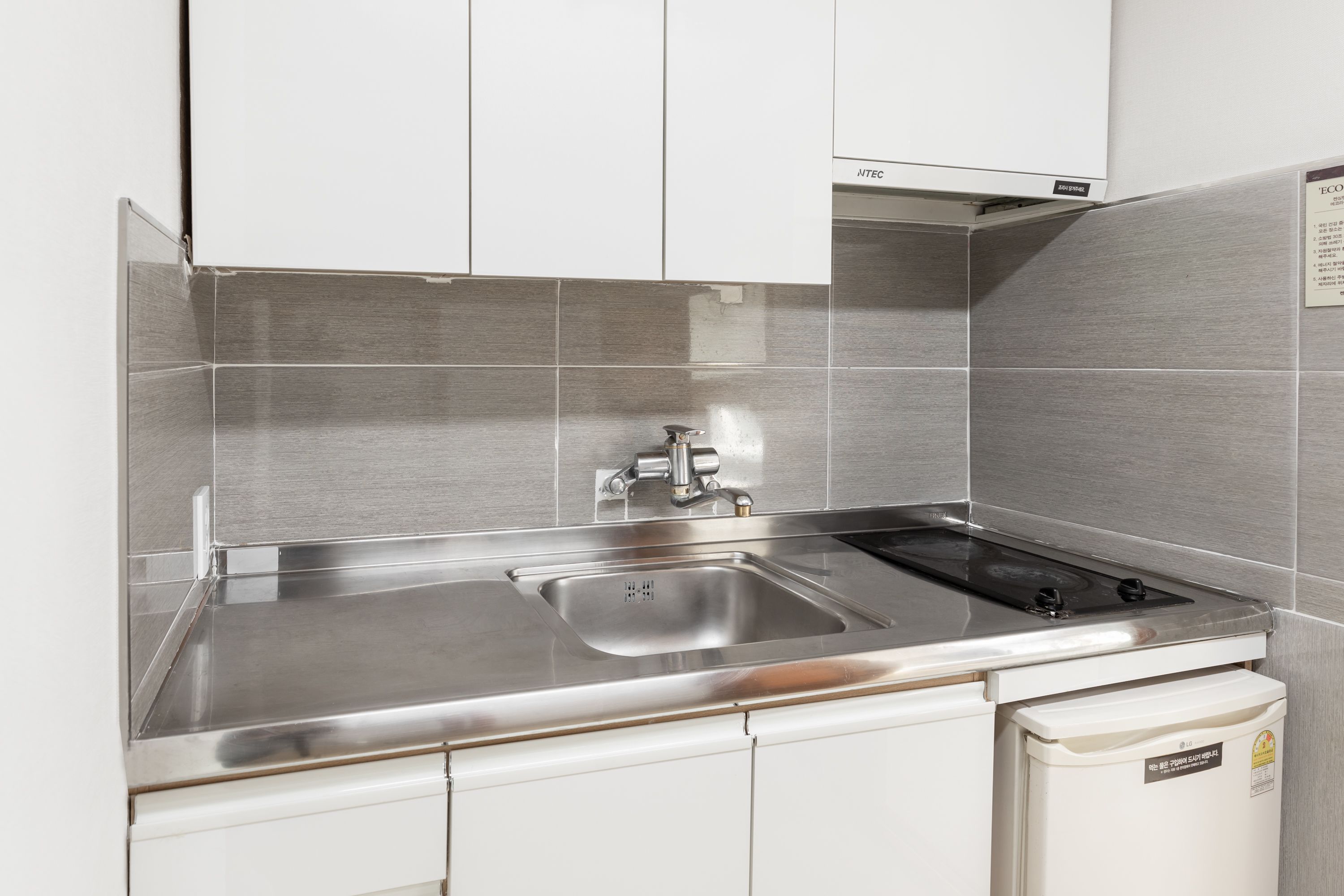 A modern kitchen with stainless steel appliances, a double sink, and white cabinetry.