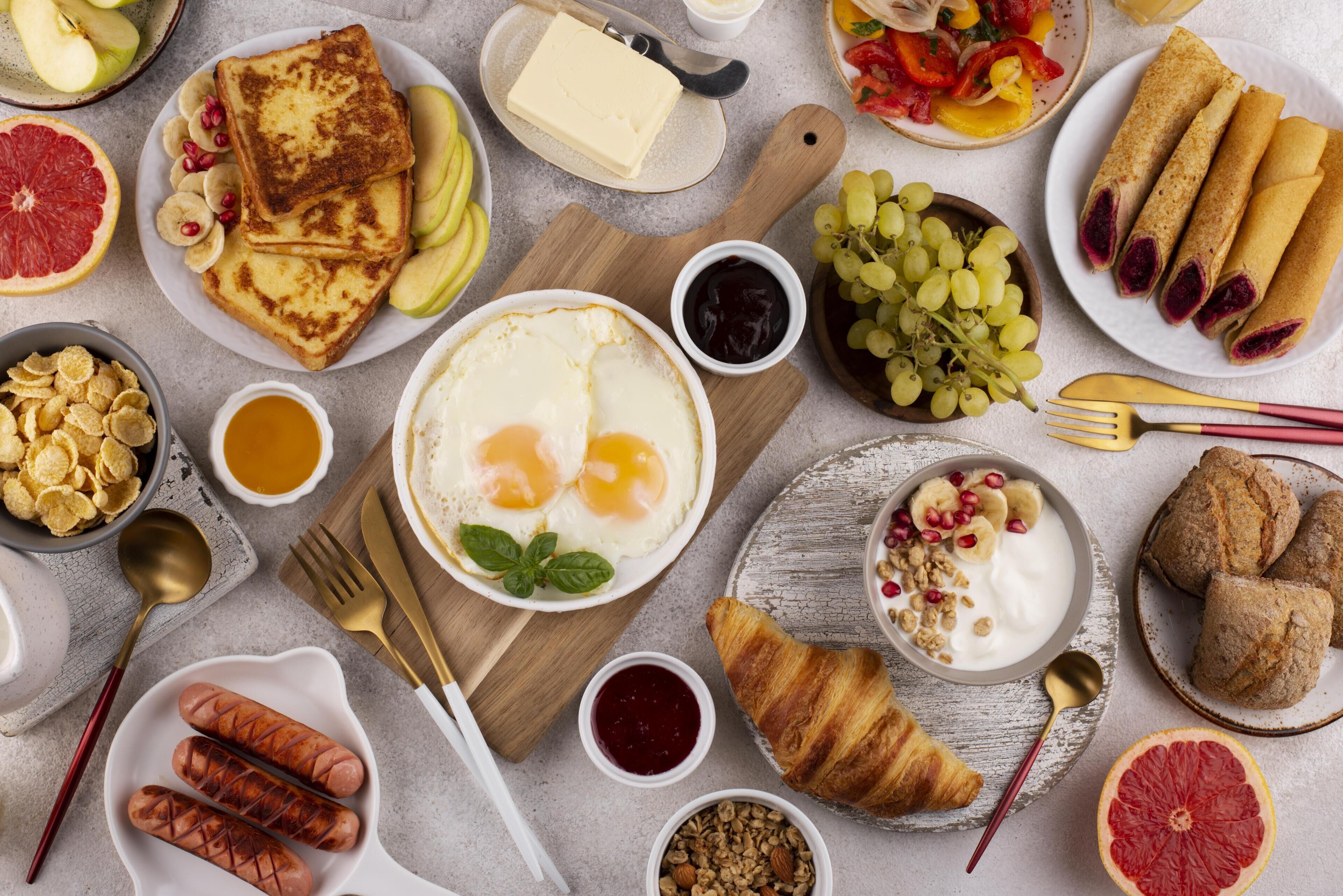 A breakfast spread with various foods including toast, eggs, sausages, and pastries.