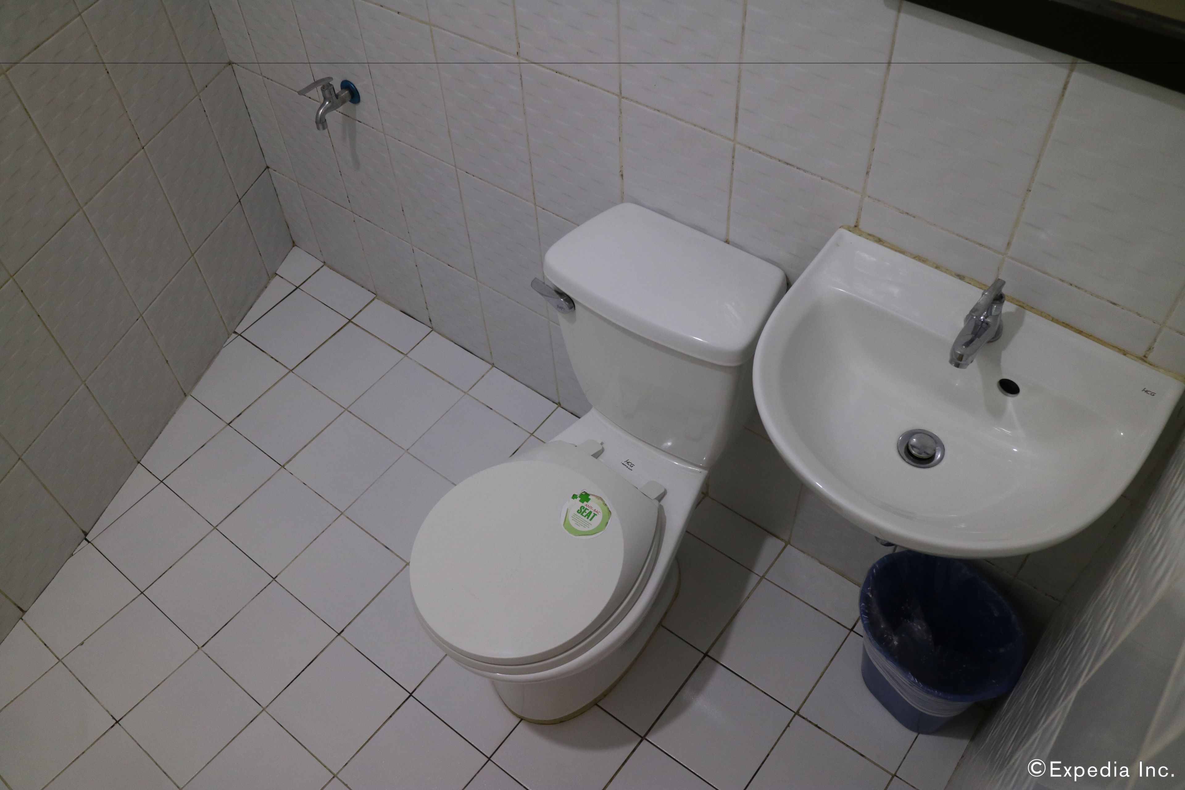 A bathroom with a toilet, sink, and trash bin.