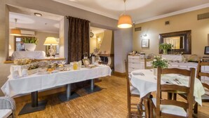 A dining area with a table set for two, a hanging light fixture, and a mirror above the table. - American House Baletowa (Warsaw)