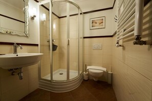 A bathroom with a glass-enclosed shower, a sink, a toilet, and a towel rack.