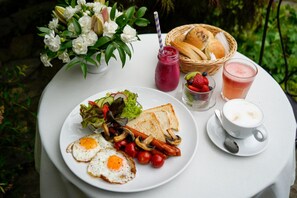 A table with a plate of food, a drink, and a basket of bread. - American House Baletowa (Warsaw)