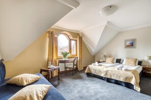 A hotel room with a bed, a desk, and a chair. There is a window with curtains, a painting on the wall, and a lamp on the nightstand. - American House Baletowa (Warsaw)