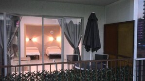 A hotel room with two beds, a small desk, a chair, and a window with curtains. - Apartamentos Bermudas (Benidorm)