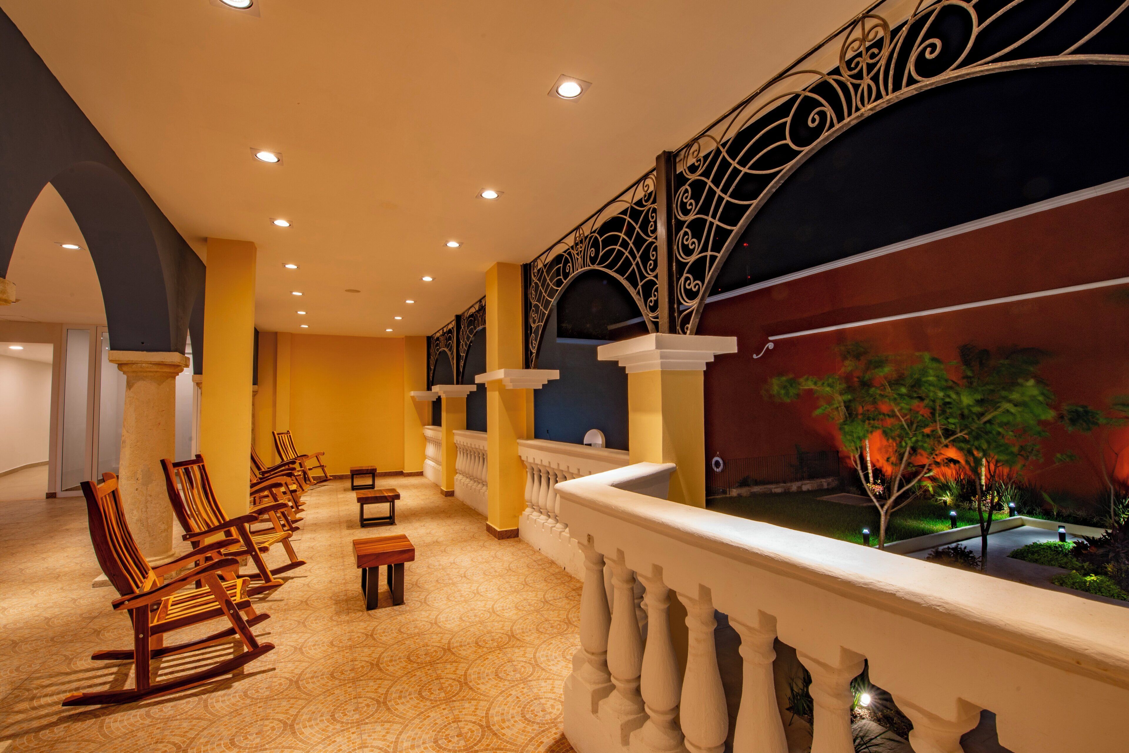 Un vestíbulo de hotel con zona de estar, columnas y un balcón con vistas a un jardín.