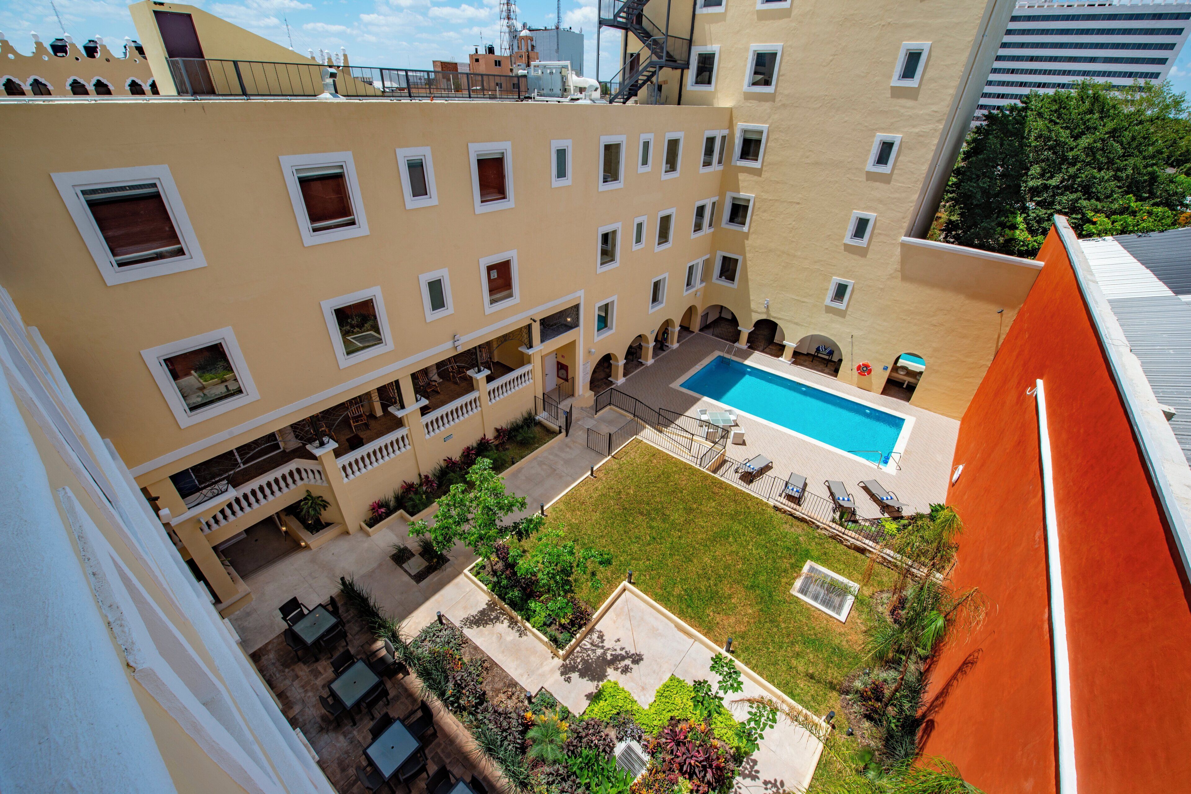 A courtyard with a swimming pool, outdoor seating, and a view of adjacent buildings.