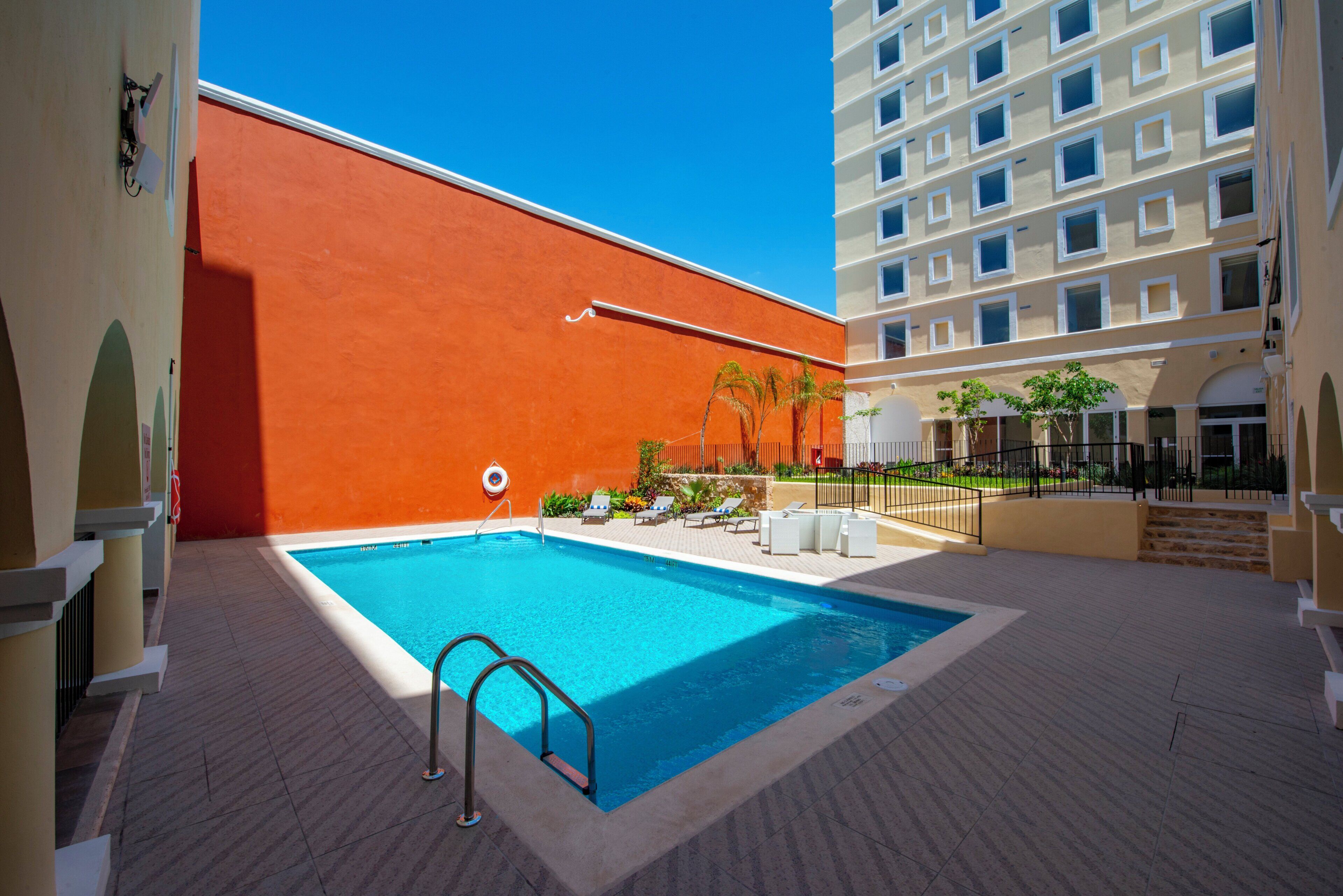A swimming pool with a lifebuoy, lounge chairs, and a clear sky.
