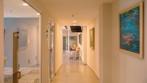 A hallway with a patterned floor, a chair, and a painting on the wall.