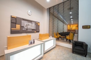 A reception area with a modern design, featuring a reception desk, a clock, and a decorative wall panel. - Holiday Inn Express Merida Centro by IHG (Mérida)