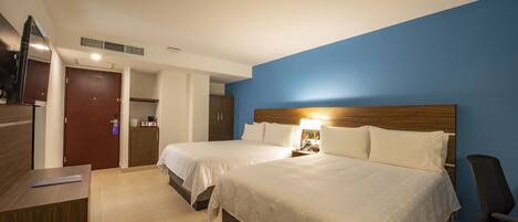 A hotel room with two beds, a desk, a chair, and a television.