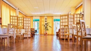Una habitación amplia con suelo de baldosas, sillas de madera y una planta en maceta en el centro.