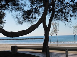 Un banco con vistas a una playa y al mar, con una costa rocosa.