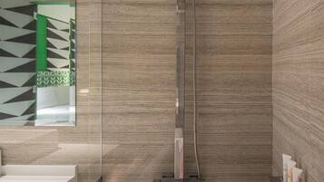 A modern bathroom with a glass-enclosed shower, a freestanding bathtub, and a tiled wall with a geometric pattern.