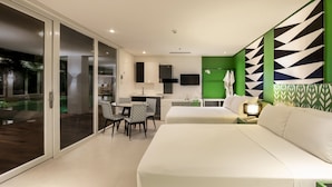 Une chambre d’hôtel moderne avec un grand lit, un bureau avec une chaise, une petite table et un mur d’accent vert.