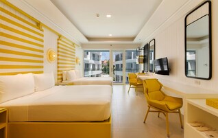 Quarto de hotel com uma cama grande, uma escrivaninha, uma cadeira e uma televisão.