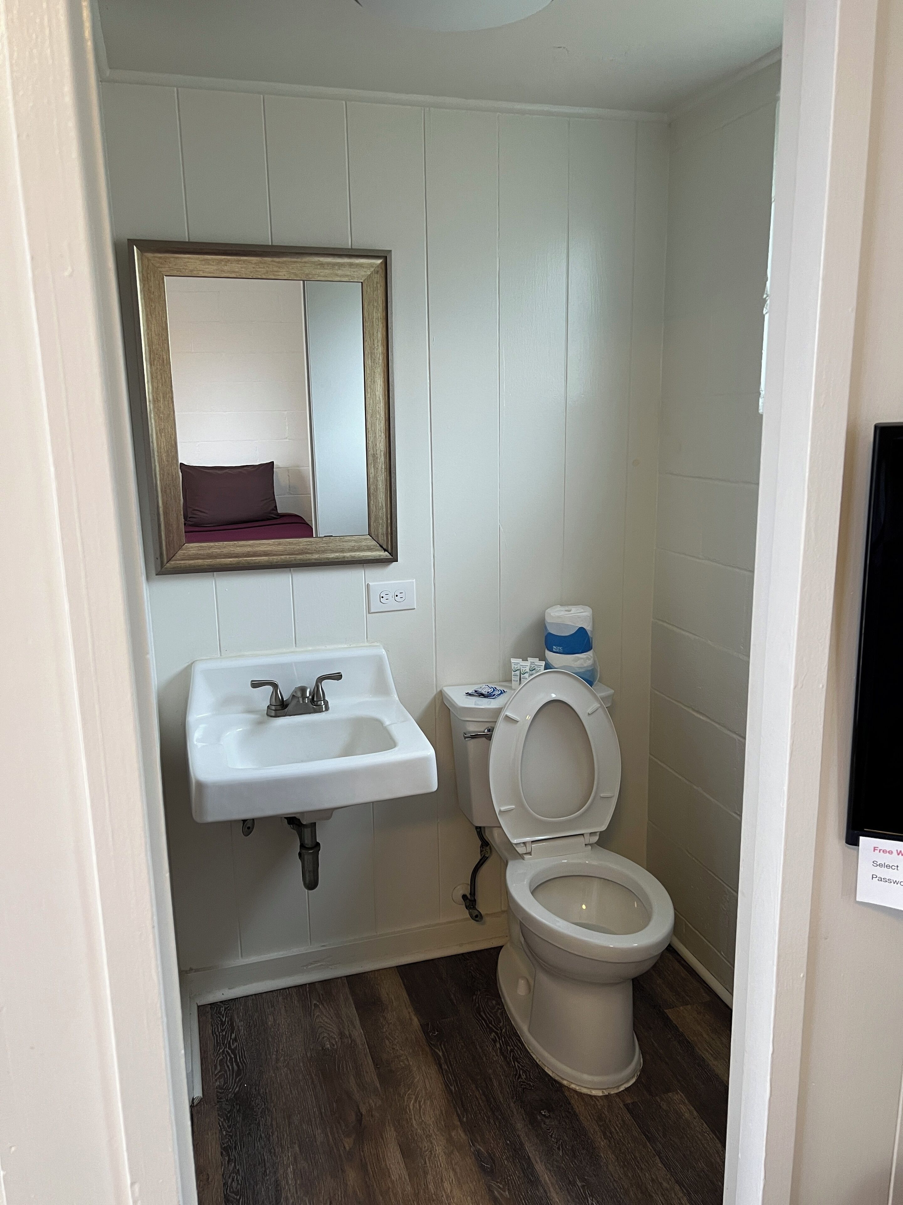 A small bathroom with a white sink, a mirror, and a toilet.